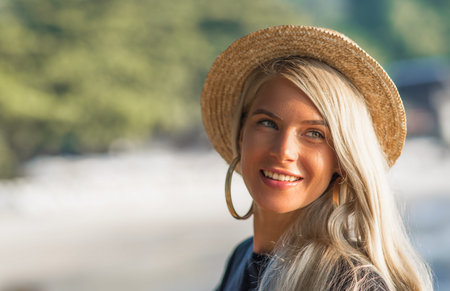 Portrait of a happy young girl. Morning sitting on sandy beach, smiling at camera. Closeupの写真素材