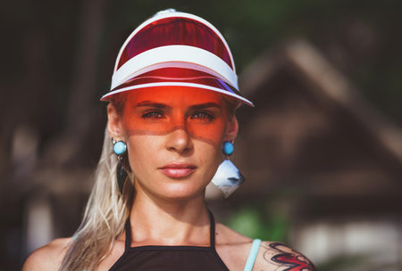 Portrait of a beautiful girl in a red visor closeup. Wearing Large turquoise earrings. Holiday in Thailandの写真素材