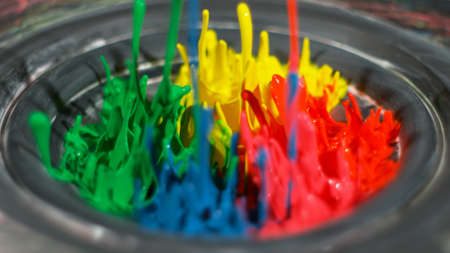 Rainbow paint splashing upwards in silver bowlの写真素材