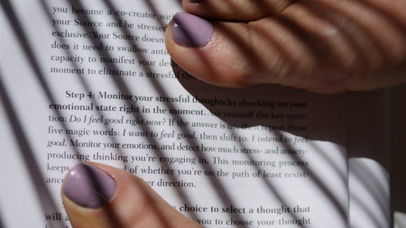 Woman reading a book with shadow from the palm of her hand.