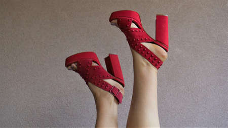 Female legs in red high heel sandals on a gray background.の写真素材