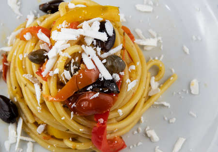 Bucatini pasta with peppers, capers, olives and cherry tomatoesの写真素材