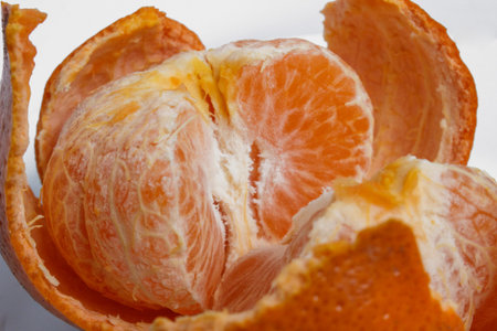 Closeup view of a peeled tangerine split in half with a white background