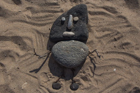 Little man with stones on the sandの写真素材