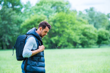 Travel. Young man with a bag on green nature background thinking and look down.の写真素材