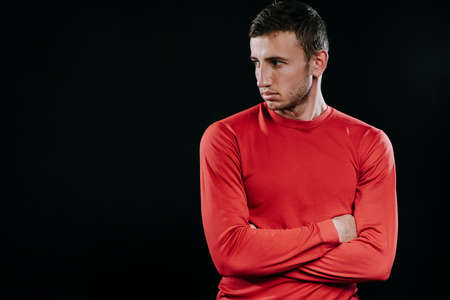 Portrait of handsome Caucasian sportsman wearing red sportswear and posing after exercises on dark background. Healthy inspirational fitness lifestyle, sport motivation.の写真素材