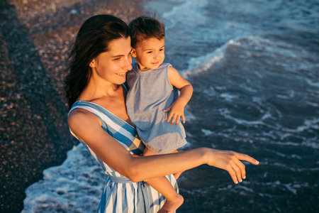 Top view of beautiful mother hugs daughter on the sea and beach background. Happy family in vacation...