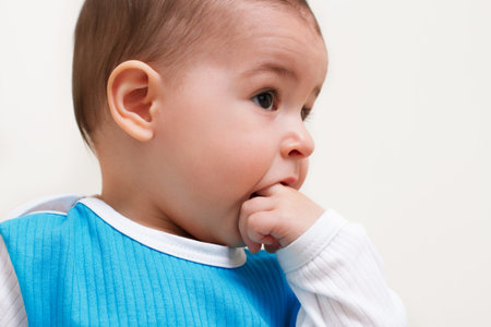 Close up portrait of adorable baby toddler with fingers in mouth