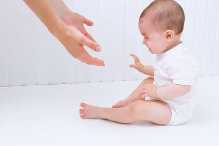Beautiful baby with mother hands help on white backgroundの写真素材