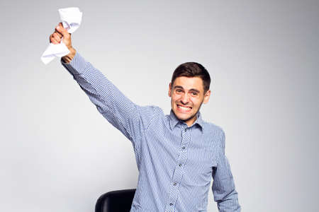 Emotional business man with paper on gray backgroundの写真素材