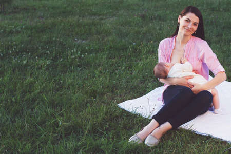 breastfeeding. mother feeding her baby in nature outdoors in the parkの写真素材