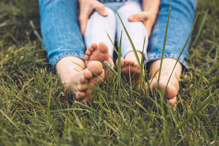 Closeup image of beautiful woman's feet embrace her girl's legs outdoor. Loving mother and daughter...
