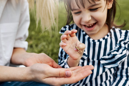 Closeup portrait of happy little girl explores the nature outdoor. Loving mother and daughter spend...