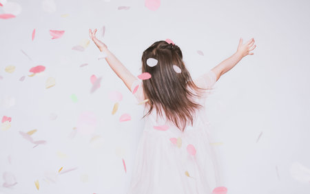 Rear view image of little girl wearing pink dress in tulle with princess crown on head isolated on...