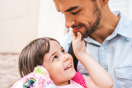 Closeup portrait of handsome happy young father embrace his daughter after preschool day. Cute...