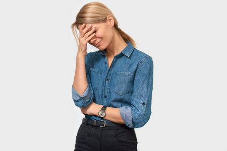 Exhausted young female touching her forehead with closed eyes posing on white studio background....