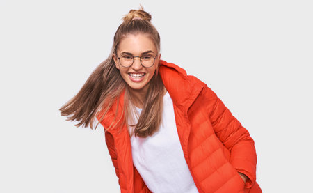 Beautiful blonde young woman laughs at something funny, dressed in white t-shirt and red jacket,...