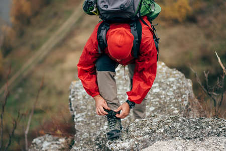 Caucasian young hiker man hiking in mountains dressed in red clothes exploring new places. Traveler bearded male trekking and mountaineering during his journey. Travel, people, sport, lifestyle conceptの写真素材