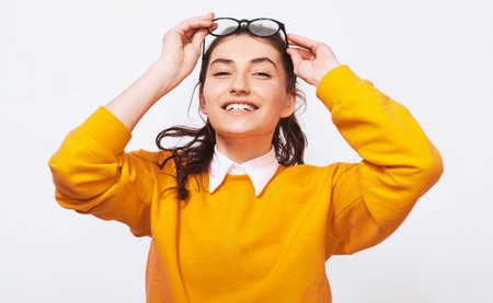 Happy beautiful young woman, smiling broadly, wears orange sweater with white shirt and round...