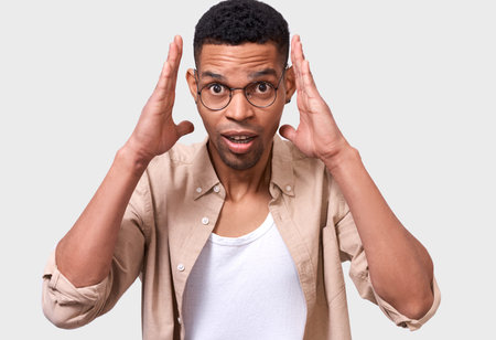 Amazed handsome Afro young man looks surpried, wearing casual outfit, isolated over white studio...