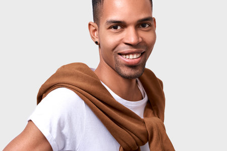 Horizontal close up portrait of handsome dark-skinned man smiling wears casual stylish outfit,...