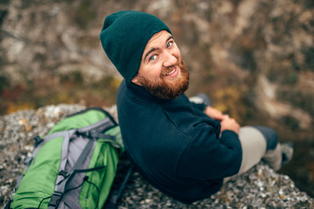 Outdoors rear view  portrait of happy hiker young man in green hat, feel good after hiking in...