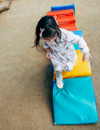 Image of happy cute little kid girl playing on colorful playground outdoor. Playful child running and jumping outside. Happy and healthy childhood. Activity kids educational conceptの写真素材