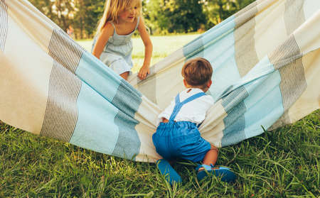 Playful children, sister and brother playing on the blanket. Happy little boy and little girl enjoying summer day in the park. Cheerful kids playing outdoorsの写真素材