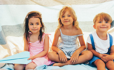 Cute children sitting on the blanket, playing together. Happy little boy and little girls smiling...