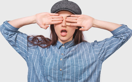 European young woman in casual outfit, covering her eyes, has a surprised face, waiting for a...