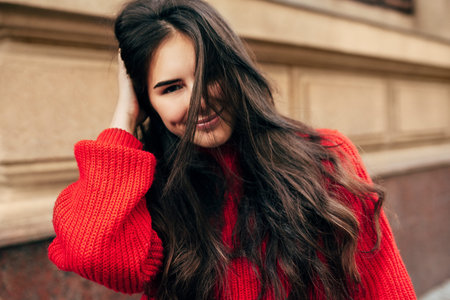Smiling European brunette woman with long hair looking directly to the camera. Outdoor portrait of...