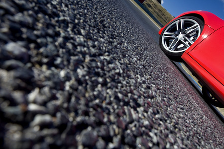 Close view of the wheel of a red sport car With The asphalt at foregroundの写真素材