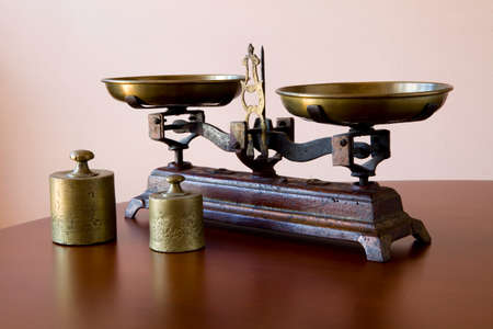 Old scales on a wooden table with two golden weightsの写真素材