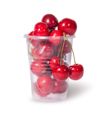 Red juicy sweet cherries in a plastic cup isolated on white backgroundの写真素材