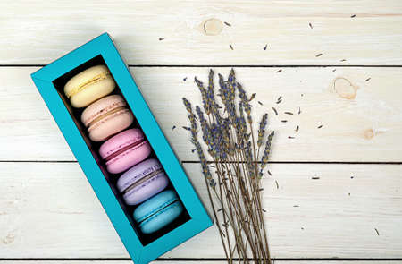 Macaroons in gift box next to lavender on wooden backgroundの写真素材