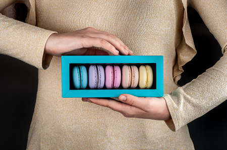 Female hands holding multicolored macaroons in gift boxの写真素材