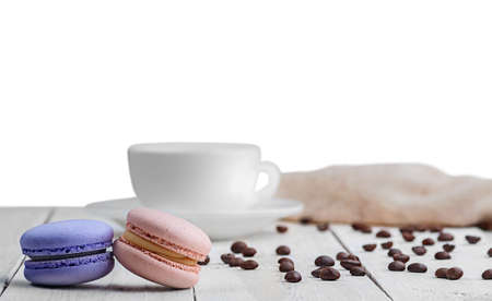 Two macaroons with a cup, coffee beans and towel isolated on white backgroundの写真素材