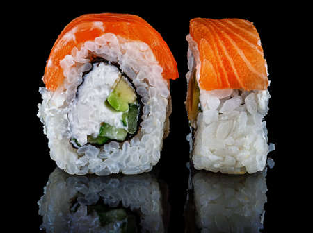 Two pieces of rolls Philadelphia. Black background. Reflection.の写真素材