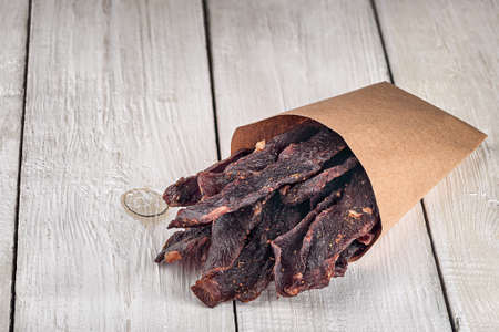 Jerky in a paper bag on top on white tableの写真素材