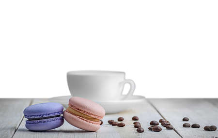 Two macaroons white table with a cup and coffee grains isolated white backgroundの写真素材