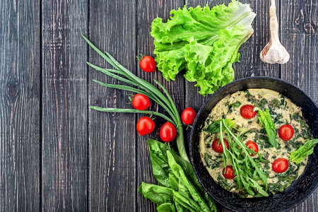 Fritatta and ingredients. An old frying pan on a wooden table. View from above. Free space.の写真素材