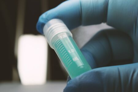 Gloved Hand Holding Zika Vial, Gloved Hand holding research vial with colored substanceの写真素材