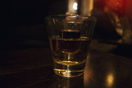 A glass of Strong alcohol inside a glass of energizer, two glass cocktail, in low light inside a pub  backgroundの写真素材