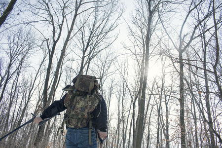 Man doing metal detecting with camouflage  backpack with forest backgroundの写真素材