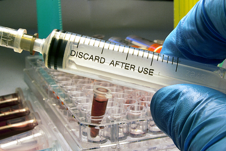 Syringe, medical injection in hand, palm or fingers. Medicine plastic vaccination equipment with needle. Liquid drug or narcotic. Health care in hospital. Gloved Hand Holding a Syringe.の写真素材