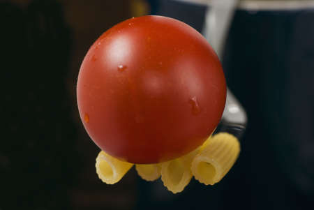 Pennette rigate and red cherry tomato on black background and selective focusの写真素材