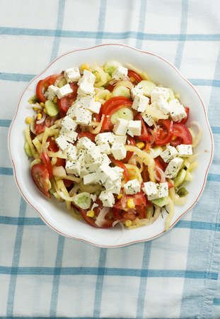 Delicious bowl of greek style salad, with tomato, onions, feta cheese and cornの写真素材