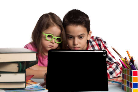 Brother and sister at their desk using a tablet.の写真素材
