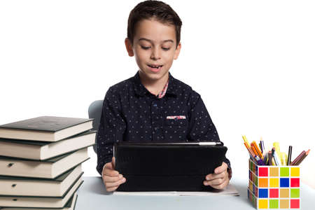 Happy student doing his homework at his desk using a digital tablet.の写真素材