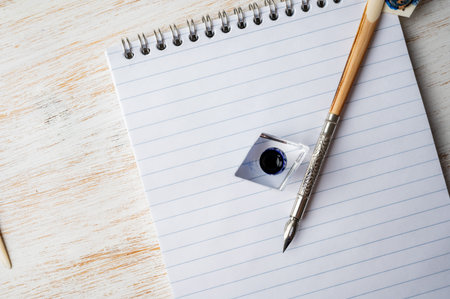 Vintage ink pen in female hand, notebook with lines and blue ink